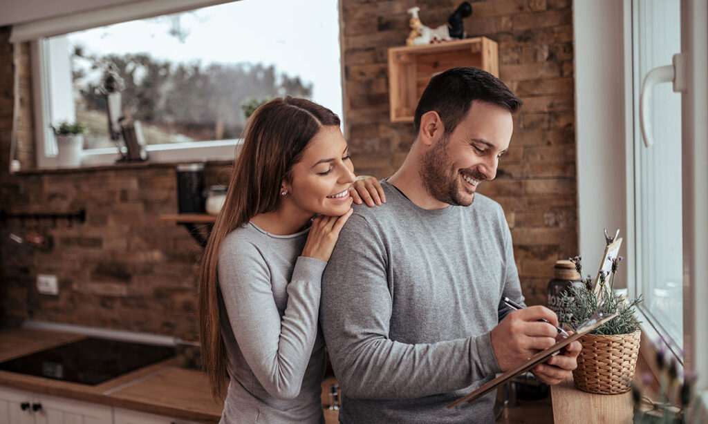 Portrait of a cute millennial spouses writing a list at modern c