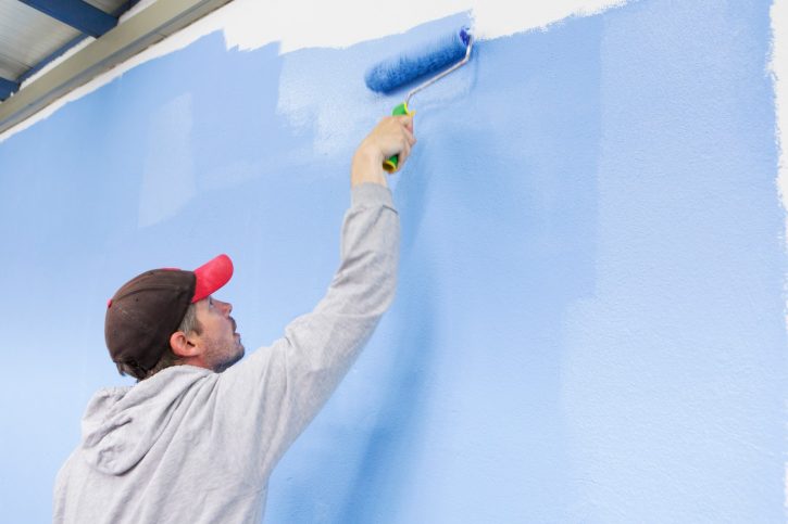 Man painting blue wall