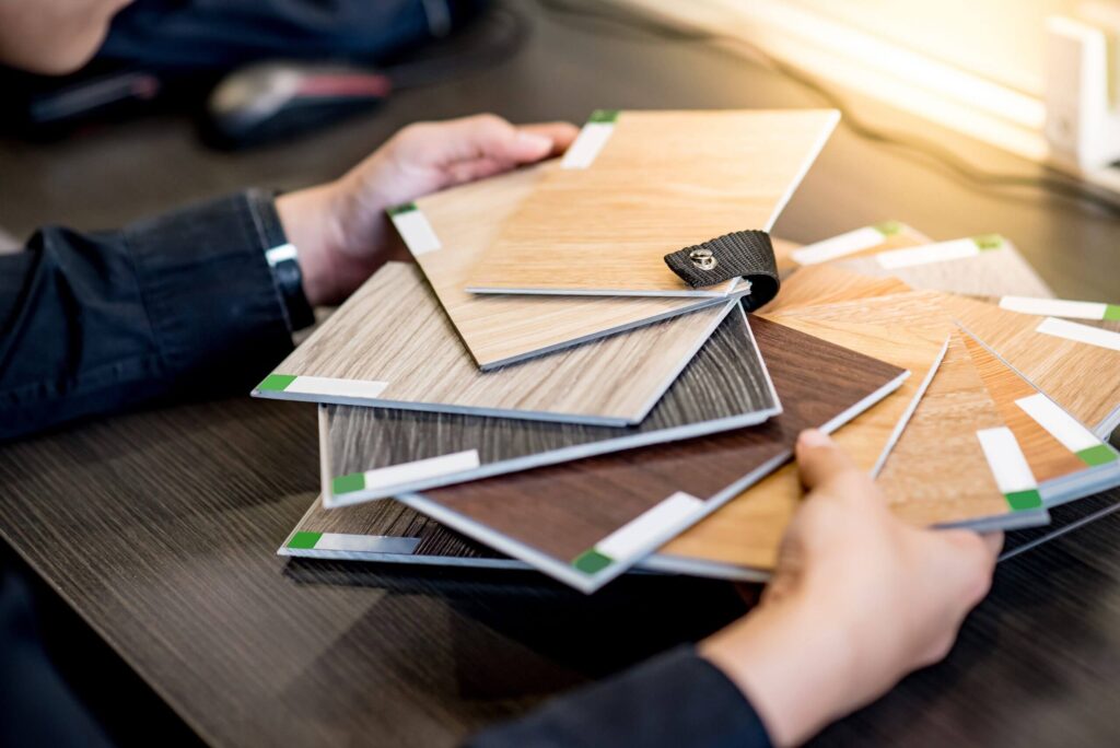 Male architect or interior designer holding wooden color swatch choosing wood material for housing project.