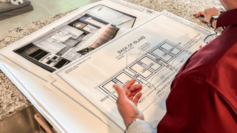 Man in maroon shirt looking over floor plans