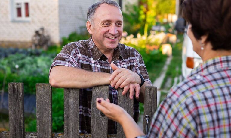 Man and woman talking over wooden fence