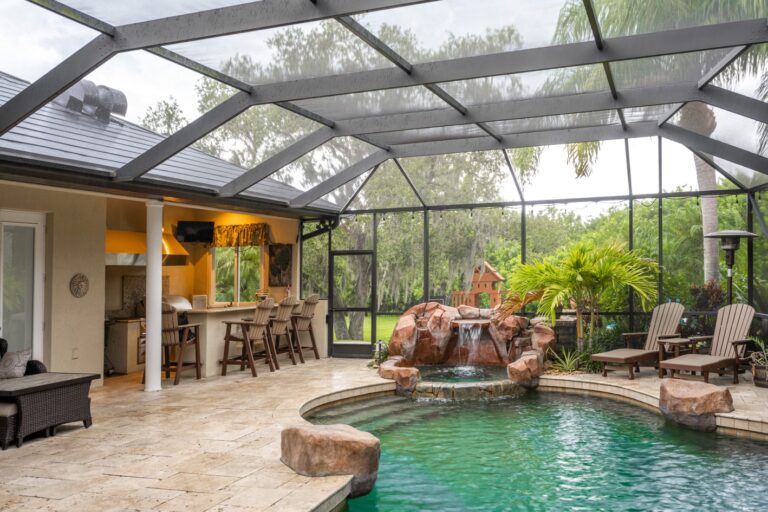 Pool with rocky waterfall next to outdoor kitchen