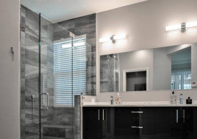 Gray shower in corner next to dark vanity