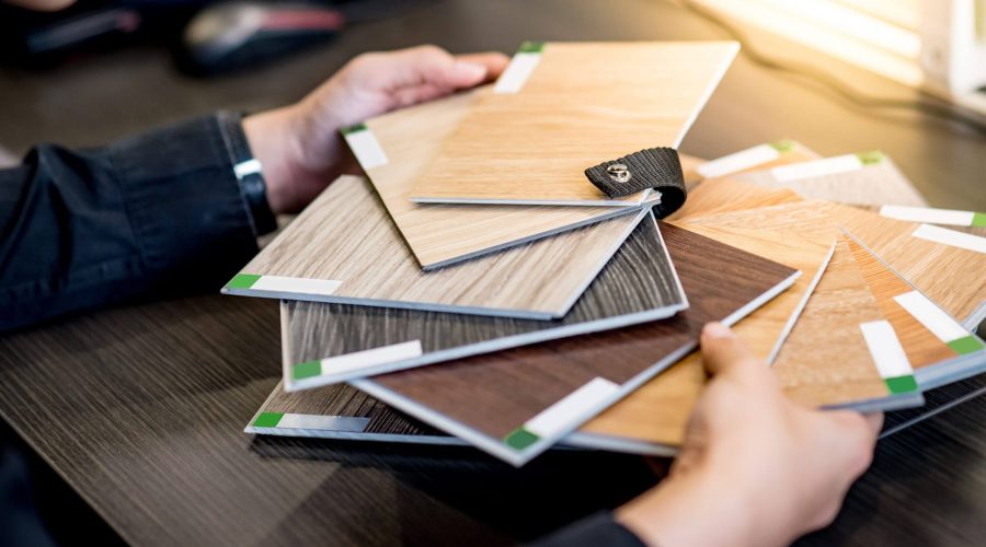 Male architect or interior designer holding wooden color swatch choosing wood material for housing project.
