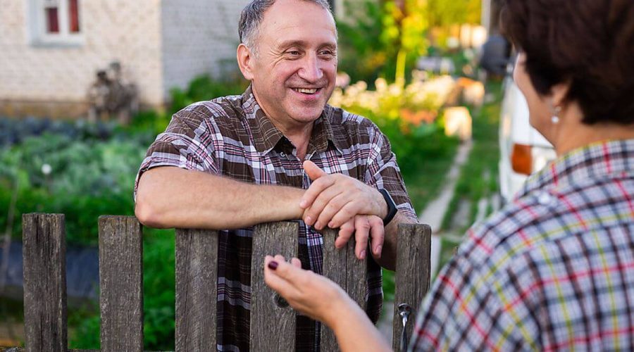 Man and woman talking over wooden fence